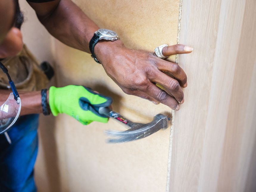 Monteur befestigt die Rückwand eines Schranks mit dem Hammer
