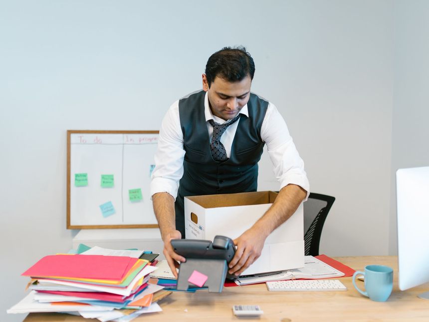 Beschriftete Umzugskartons und Bürostühle in einem leergeräumten Büro