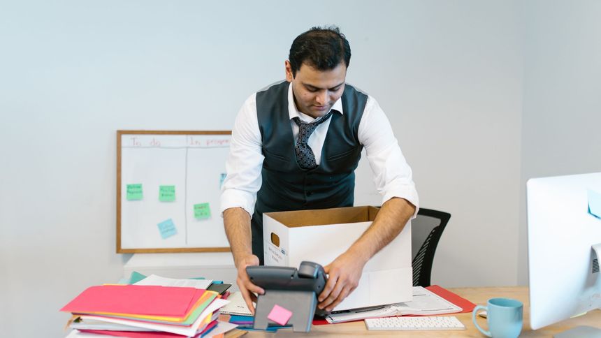 Beschriftete Umzugskartons und Bürostühle in einem leergeräumten Büro