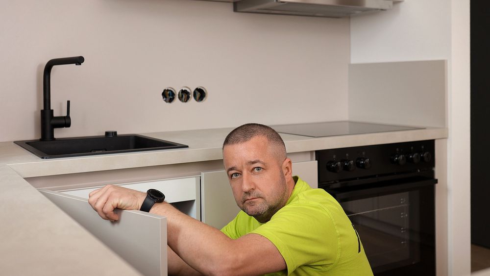 Mitarbeiter von A&V Group im Firmenshirt bei der Montage einer Einbauküche in einer leeren Wohnung