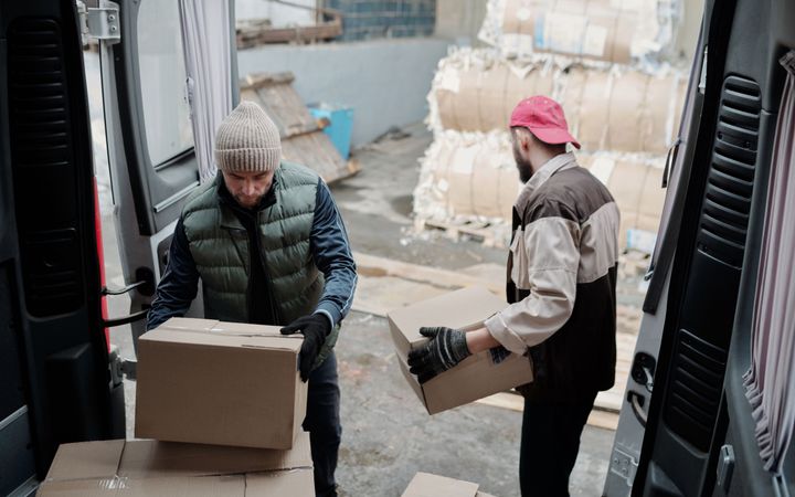 Umzugshelfer verladen kurzfristig Kartons in einen Transporter