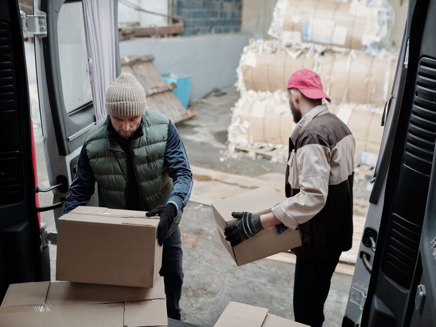 Umzugshelfer verladen kurzfristig Kartons in einen Transporter