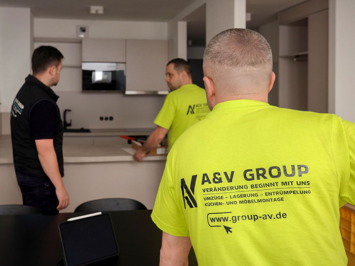 Drei Mitarbeiter von A&V Group in Firmenshirts bei der Montage in einer Küche
