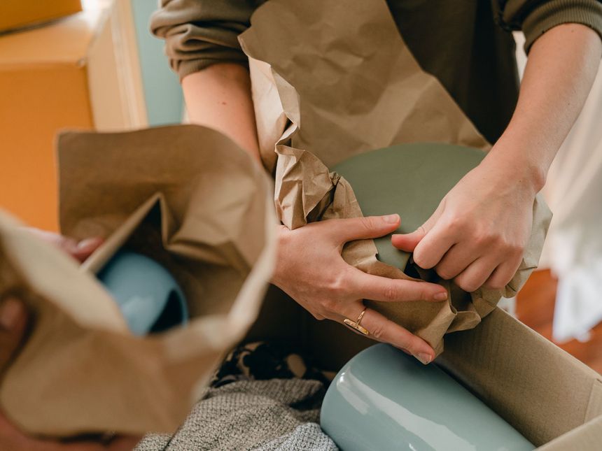 Gläser werden einzeln in Papier eingewickelt und in einen Umzugskarton gepackt